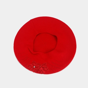 Detailed view of red knitted beret featuring a 3D floral applique with rhinestone center