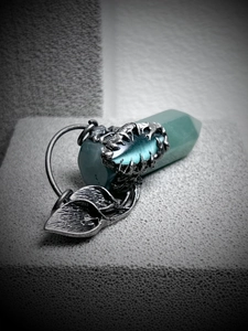 Macro view of gothic silver vine and claw wrapping a hexagonal turquoise crystal pendant