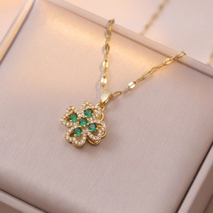 Détail d'un pendentif floral doré avec pierres vert émeraude et zircons blancs étincelants