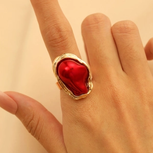 Nahaufnahme eines goldenen Rings mit rotem Edelstein, getragen an der Hand bei Naturlicht