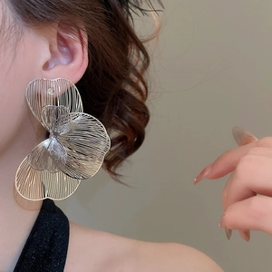 Gros plan détaillé de grandes boucles d'oreilles fleurs évidées en argent tissé