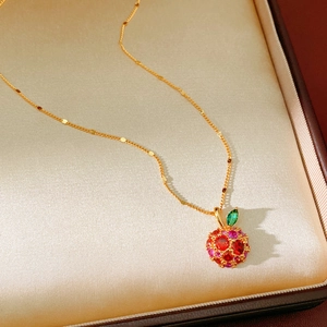 Close-up of 14k gold plated apple pendant with red zircons in a champagne satin jewelry box