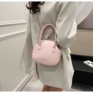 Detail of pink leather shell bag showing the retro kiss-lock closure and sturdy top handle