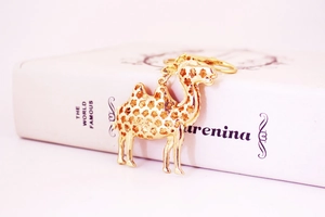 Close-up of golden camel keychain with intricate hollow patterns on a book background