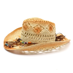 Detail of western straw hat with geometric cutouts and bohemian colorful beads with shells