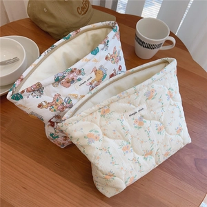 Detailed macro of quilted cotton makeup bags with floral and bear patterns on wood
