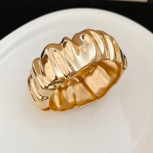 Détail macro d'une large bague croissant dorée avec texture métallique plissée polie