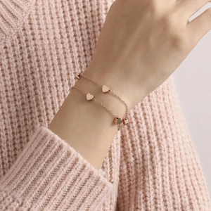 Elegant rose gold double-layer bracelet with heart pendants on a woman's wrist