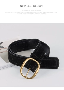 Détail d'une large ceinture en daim noir avec boucle ovale dorée sur un décor de magazine