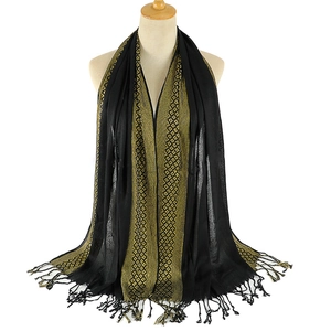 Detailed view of the gold geometric pattern and long tassels on black shawl scarf