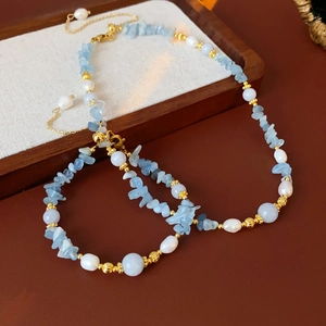 Détail du collier aigue-marine de plage avec perles blanches et accents dorés sur cuir
