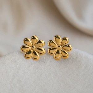 Detailed view of 18K gold plated stainless steel flower stud earrings on textured fabric