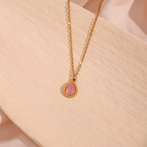 Detailed close-up of pink teardrop cat eye stone pendant with gold dotted frame