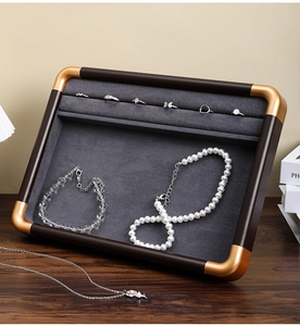 Detail of walnut wood jewelry tray with grey velvet slots and gold metal corners