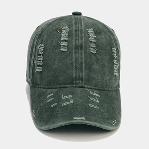 Close-up of distressed ripped details on a vintage washed army green baseball cap
