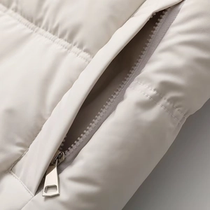 Makroaufnahme des verdeckten Metallreißverschlusses und der feinen Nähte der Steppjacke