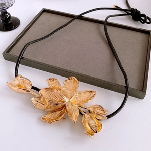 Detailed view of the gold-tone tulip pendant with intricate petals on a black leather cord