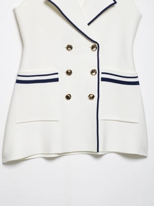 Detail of white knit vest dress featuring navy trim and gold double-breasted buttons