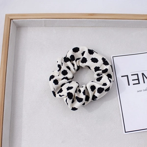 Détail d'un chouchou à pois noirs et blancs sur un plateau à bijoux en velours