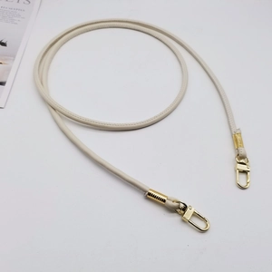 Detail of cream white PU leather strap with golden lobster clasps and metal coil detail