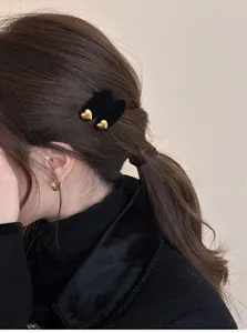 Dettaglio del fermaglio per capelli a cuore in velluto nero con incisione dorata