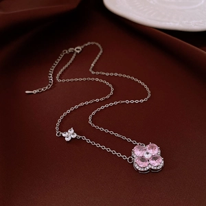 Vue détaillée du pendentif trèfle en zircon rose sur chaîne argentée et fond velours
