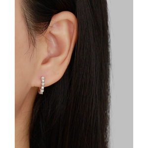 Close-up of a silver hoop earring featuring alternating pearls and clear gems on a model