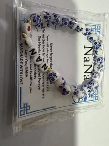Dettaglio di un braccialetto in ceramica fatto a mano con scritta NANA e fiori blu