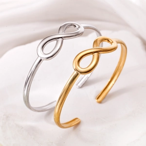 Dettaglio di bracciali rigidi oro e argento con simbolo dell'infinito su pietra bianca