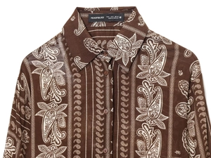 Detail of paisley print long sleeve shirt with collar label and button texture on fabric