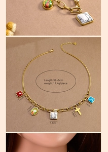 Detail of gold multi-pendant chunky necklace with cross, pearl, and colorful stones
