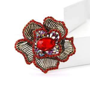 Vintage red floral brooch with rhinestones and antique gold alloy finish shown on a jewelry box
