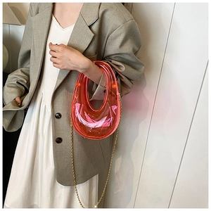 Detailed close-up of a pink acrylic U-shaped evening bag with a gold chain strap