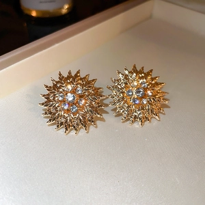 Boucles d'oreilles tournesol dorées avec strass brillants sur socle beige