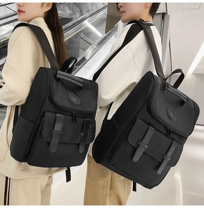 Rear view of unisex black nylon backpacks with double buckles on an escalator