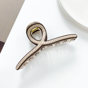 Detail view of a beige shark hair claw with dark brown stripes and metal spring mechanism