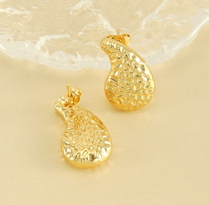 Detailed close-up of golden teardrop earrings with a textured hammered metal surface