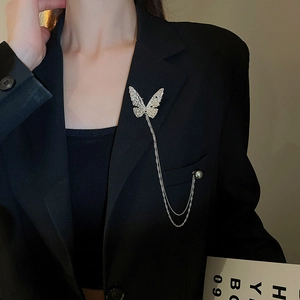 Close-up of butterfly brooch with silver fringe and pearl detail on black suit
