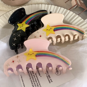 Close-up of three rainbow star claw clips with rhinestones on white ceramic plate