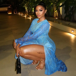 Detail of blue bodycon dress with gold leaf patterns and high side slit on model