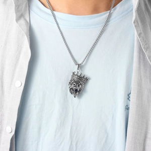 Close-up of a silver lion head pendant with a crown on a male model wearing a chain