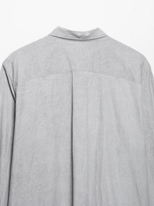 Macro view of the collar and back pleat detail on a minimalist grey cotton shirt