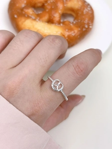 Detail of s925 silver pretzel shaped ring with twisted band texture on a hand