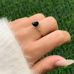 Detailed shot of handmade gold wire-wrapped ring with a black heart-shaped gemstone