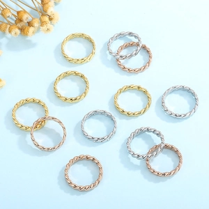 Flat lay of twisted rope band rings in gold, silver and rose gold on a blue background