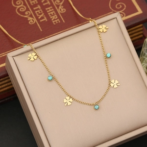 Detail of gold clover necklace with turquoise beads on vintage book background