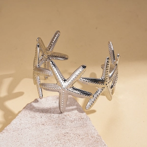 Detail shot of silver starfish open bracelet with textured finish on stone background
