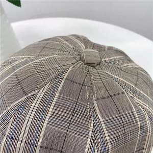 Detailed macro view of the newsboy cap crown with retro plaid pattern and top button