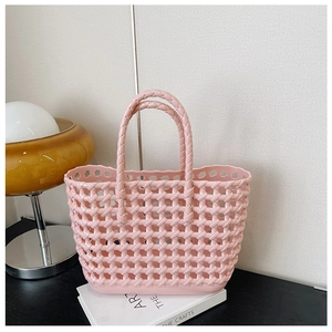Detailed view of pink woven hollow jelly beach bag on a table with professional lighting