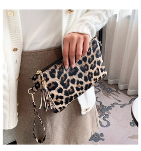 Detail of leopard print envelope clutch with fringe tassel and golden metal hardware